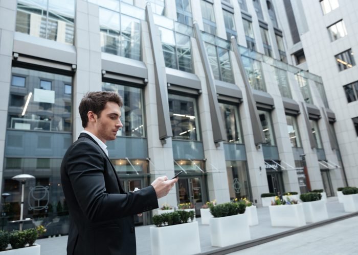 Busy young man working with smartphone in business center